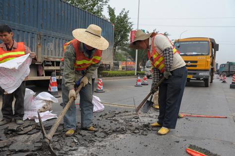 50多名市政工程管理处维修工人娴熟地铺设人行道地砖和安装路缘石,身